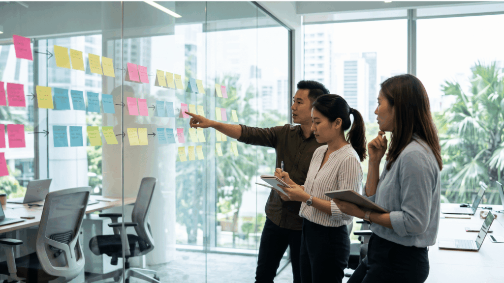 Colleagues placing sticky notes on a glass wall to plan a customer experience strategy